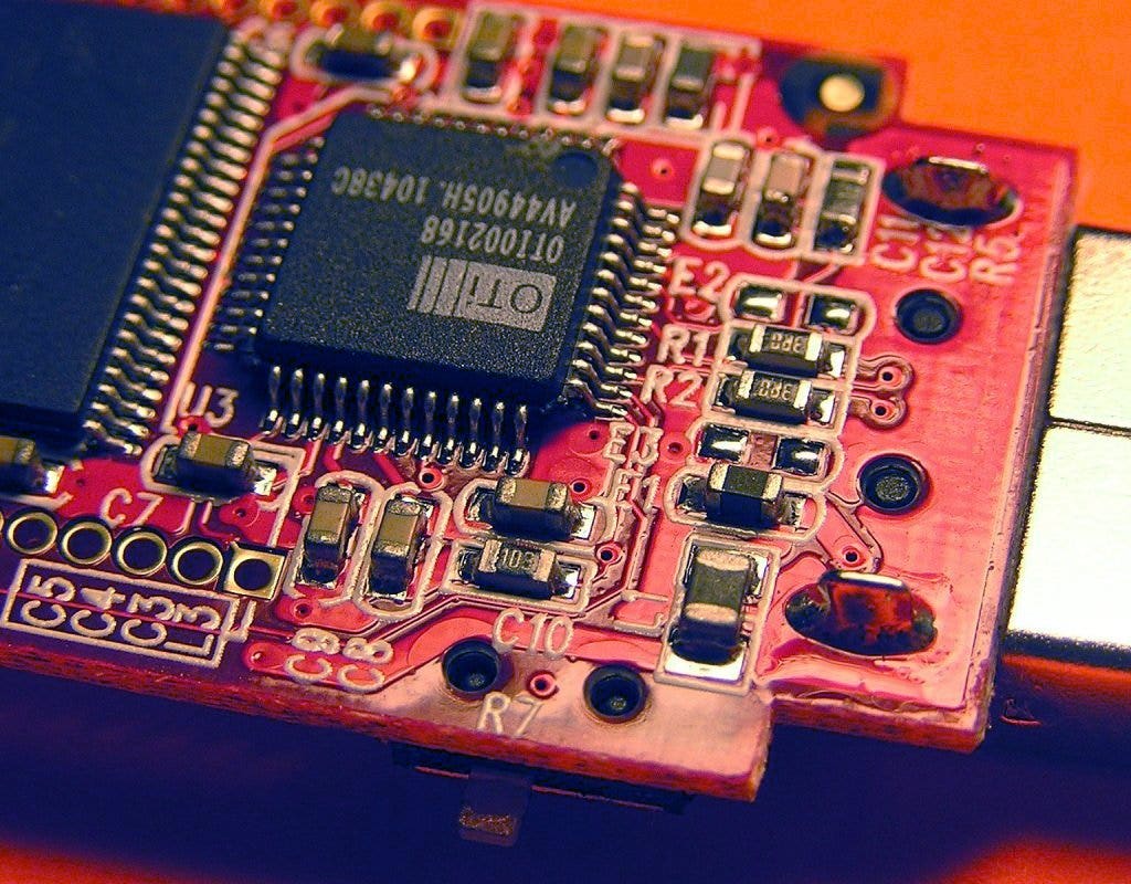 a small circuid board with some rectangular resistors, capacitors, and a large black microchip in the middle