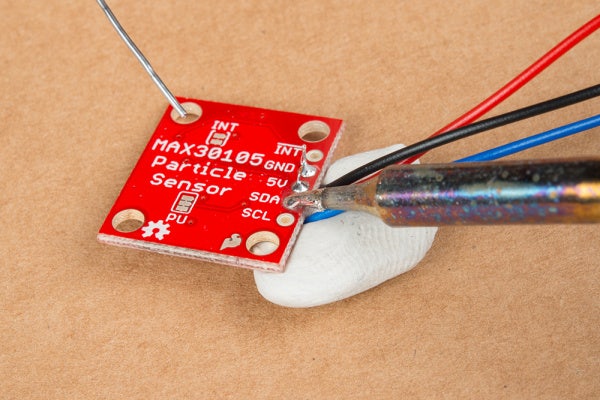 a soldering iron soldering wire to a small red circuit board