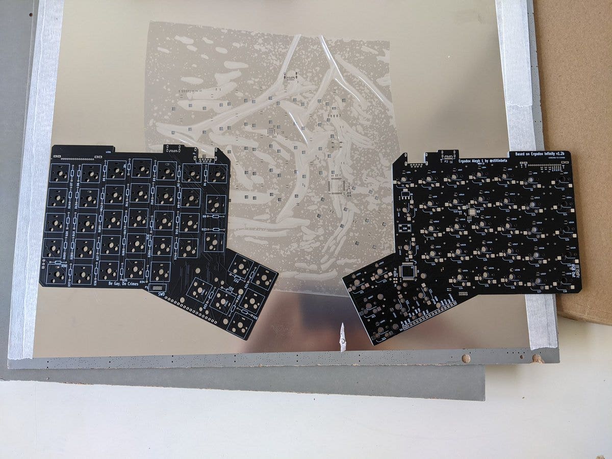 two L-shaped circuit boards, front and back, with a stainless steel sheet with some holes behind them
