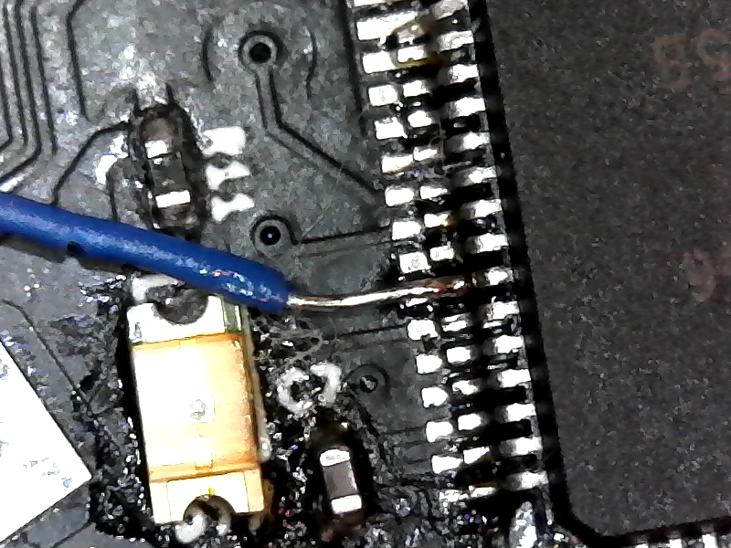 a small blue wire soldered to a single pin on a microcontroller