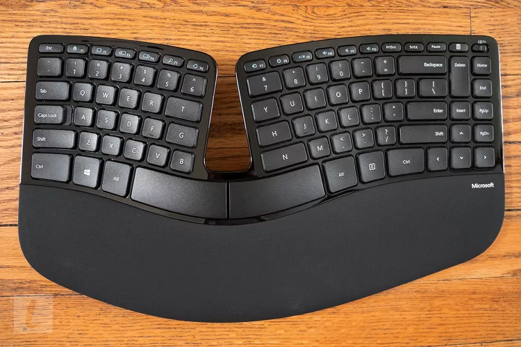 a shiny black keyboard shaped like a wave. there's a large gap in the middle. A large palm rest is at the bottom, and all the keys are visibly flat.